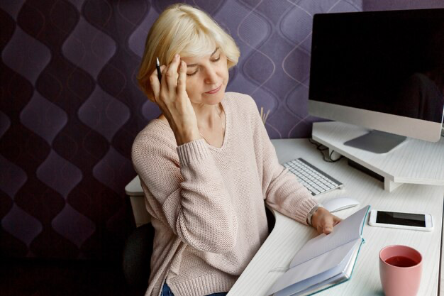 Woman reading a book and holding her head