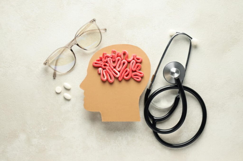 A paper cut-out head with a brain, pills, glasses, and a stethoscope